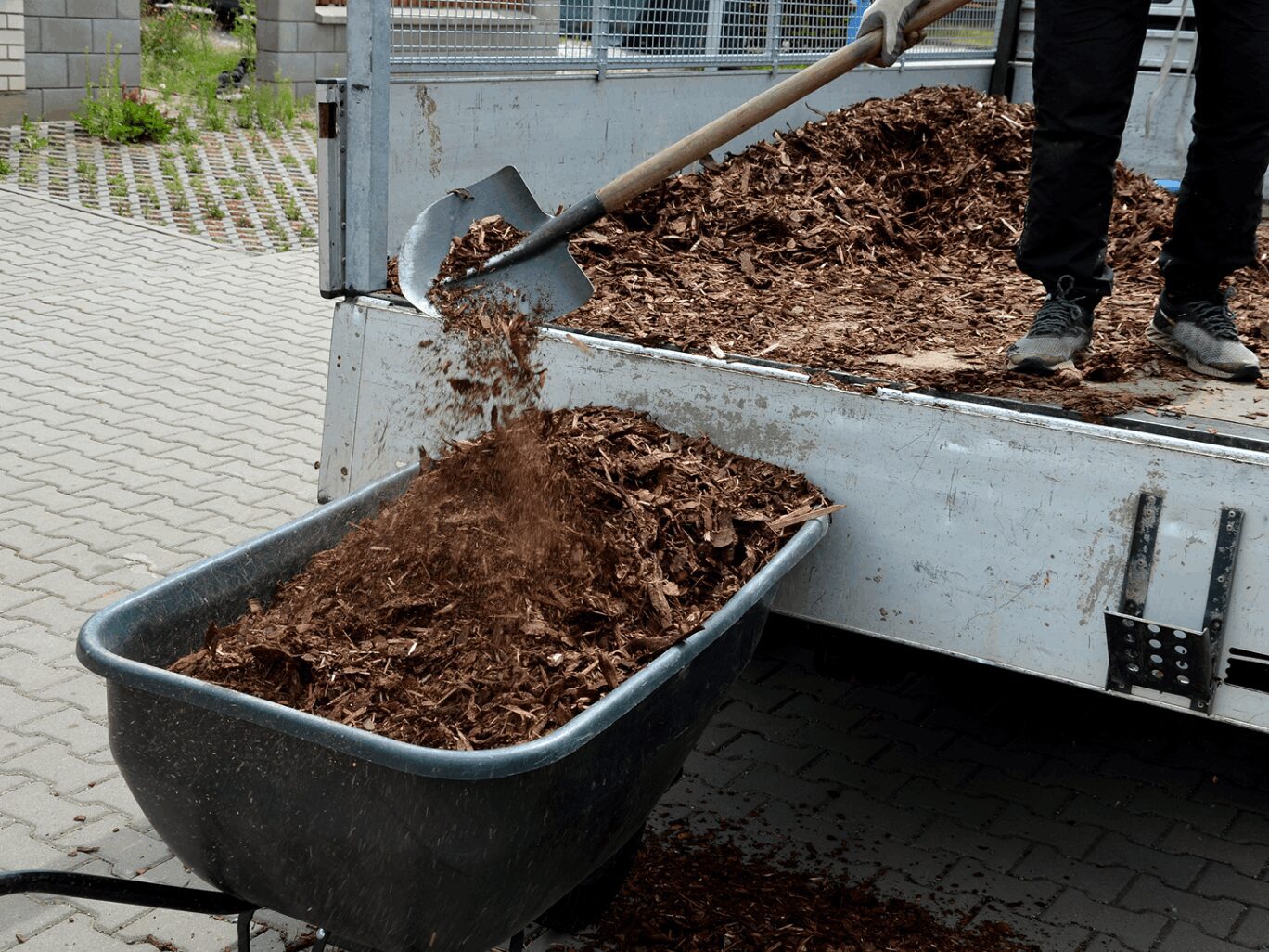A person dumping dirt into a trailer.
